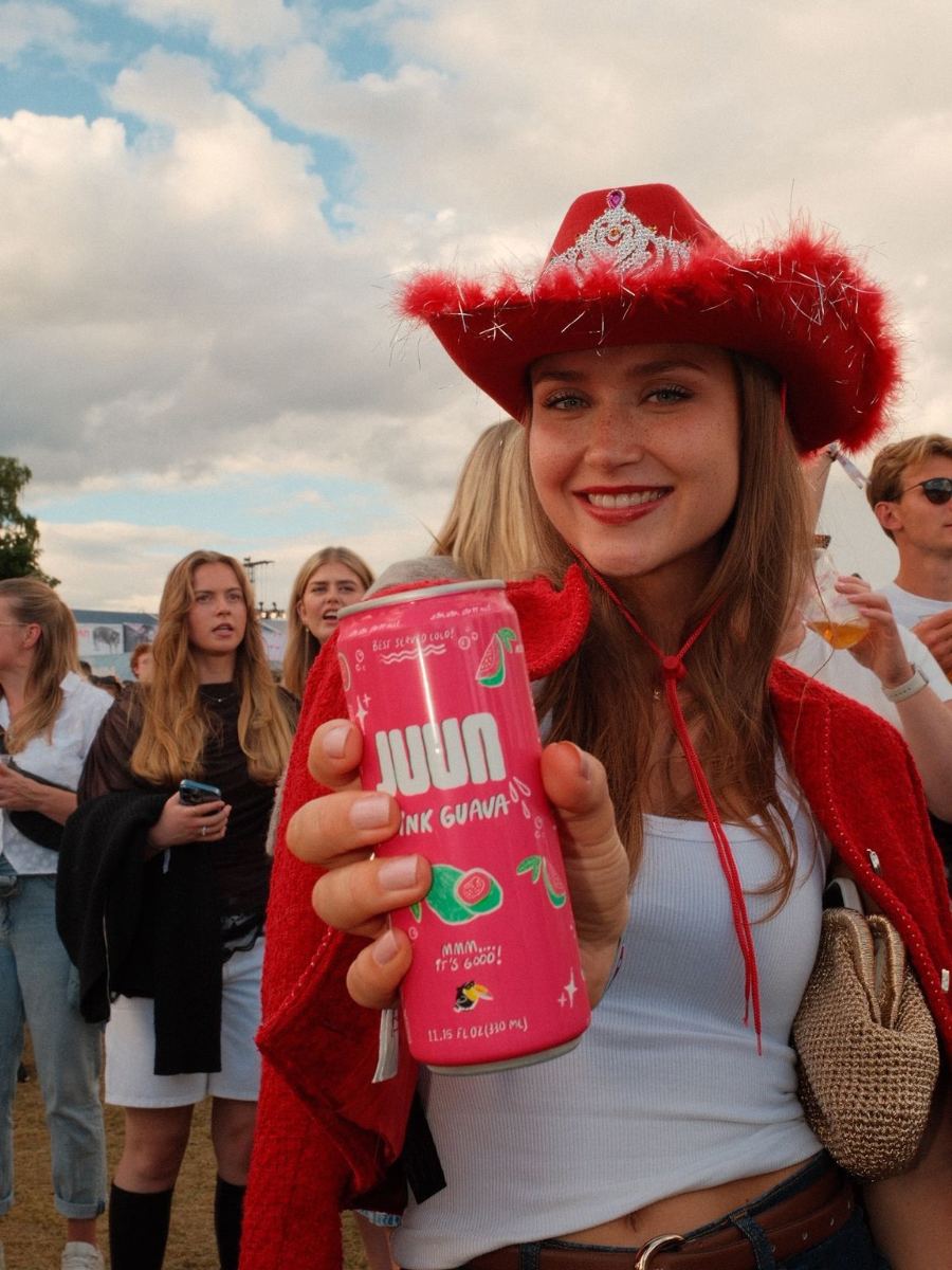 Festival-goer in a red cowboy hat holding a pink guava JUUN can
